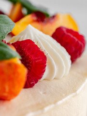 Close-up of a creamy cake's top with whipped cream and fruits.