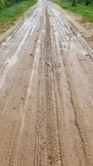 A dirty country road. After the rain, puddles, mud and traces of the car tires were formed. Shot on a phone