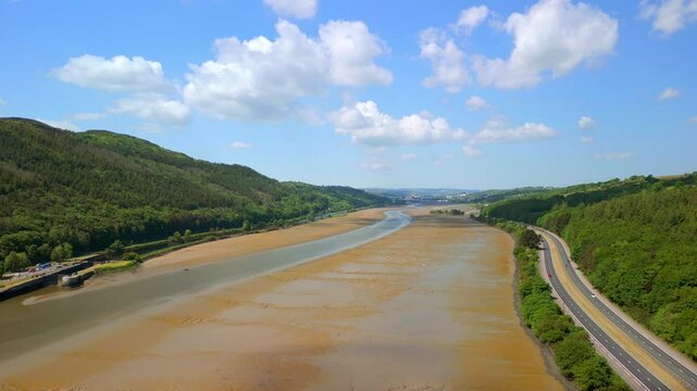 Low, rising aerial video of the Newry River and Mourne Mountains in Warrenpoint, County Down, Northern Ireland, UK on a bright and sunny day. Filmed in 4K, 60FPS and with Rec709 color.