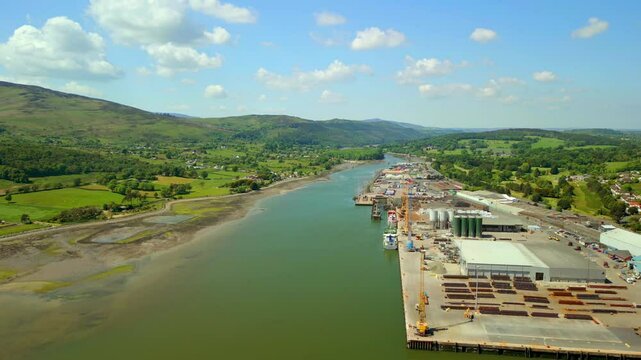 Wide, advancing aerial video of the Newry River and surrounding industry in Warrenpoint, County Down, Northern Ireland, UK on a bright and sunny day. Filmed in 4K, 60FPS and with Rec709 color.