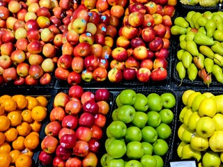 A colorful assortment of fresh, ripe apples, oranges, and pears neatly displayed in crates at a bustling market, highlighting healthy eating and abundance.
