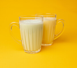 Vanilla milk shake in glass. Milkshake on yellow background, white whey protein smoothie