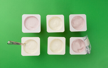Yogurt cups set, pink and yellow fruit yoghurt in plastic pots, milk pudding container with spoon