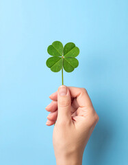 Una mano con un trébol de cuatro hojas en concepto de buena suerte, destino o fortuna sobre fondo azul