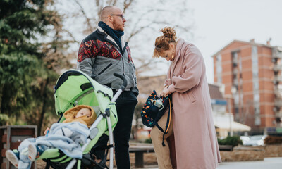 A young family spends time outdoors, with the baby comfortably seated in the stroller as they...