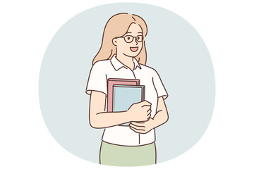 Young girl student stands with books in hands posing with glasses and looking at screen