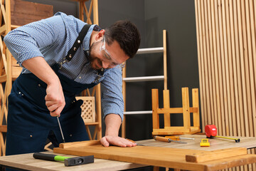 Relaxing hobby. Man working with wooden plank and screwdriver at table in workshop