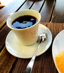 Cup of black coffee on a wooden table with spoon in natural morning light