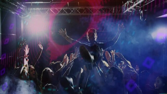 Performer stepping onstage raising arms energizing music fans crowdsurfing under colored beams