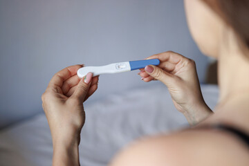 Health, pregnancy and family concept. Woman holding pregnancy test. Back view. Positive test.