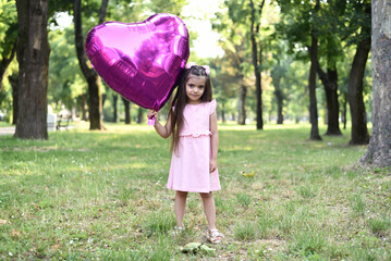 Little girl of 4 years with a big pink heart balloon