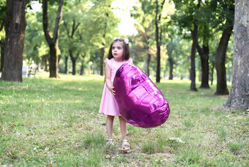 Little girl of 4 years with a big pink heart balloon