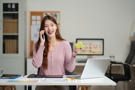 Female coder or developer  talking mobile phone working  and on computer display in problem solving at workplace.