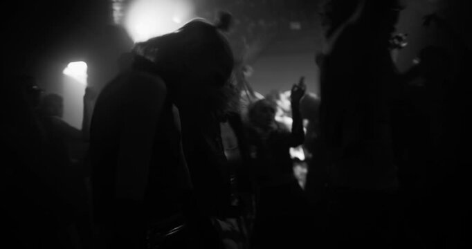 Young Man Enjoying the Party in a Nightclub Scene with Ecstatic People Dancing Under Flashing Neon Lights. Emotional Crowd Moves to Electronic Beats on a Packed Dance Floor. Black and White Footage