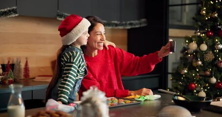 Happy mom, child and christmas with selfie in kitchen for baking memory or picture together at home. Mother, kid or daughter with smile for festive celebration, capture moment or cookies at house - Powered by Adobe