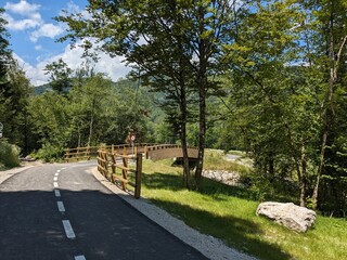 Cycling path running through river valley surrounded by high mountains of Austrian Alps offering scenic nature ride.