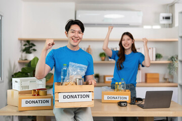 Donation and Community Support. Young volunteers celebrating successful food drive in a modern workspace.