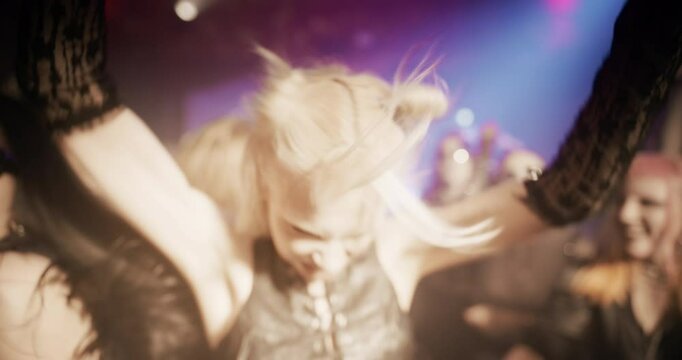 Energetic Woman with Blonde Hair Revels in a Vibrant Rave, Surrounded by a Lively Crowd Under Pulsating Lights, Capturing the Essence of Nightlife Euphoria and Dance Excitement. Slow Motion Footage
