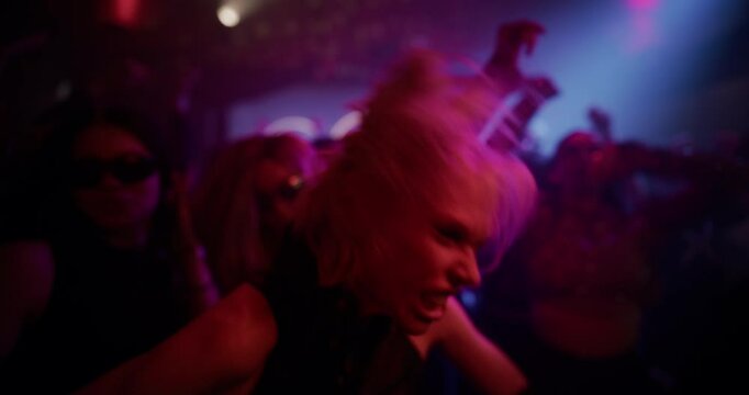 Female Turning Her Head to Look at Camera, Starts Aggressively Dancing with Diverse Crowd to Energetic Electronic Music at a Night Club Party with Colorful Lights and Lively Electrifying Atmosphere