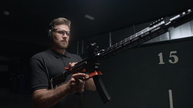 Low angle view of Caucasian man in goggles reloading rifle and starting shooting practicing in range