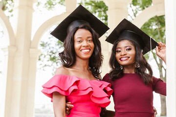 Two female college graduates smiling and celebrating graduation