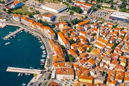 Fototapeta aerial view of the harbor of Senj with lined boats, waterfront buildings, and the charming old town with narrow streets and a central church, all bathed in sunlight