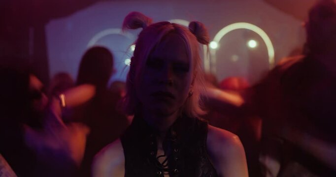 Portrait of a Tired Female Partygoer Standing Still Amid the Chaos of a Club. Timelapse Footage of People Dancing Behind Her. Her Expression is Sad, Disconnected From the Celebration Around Her