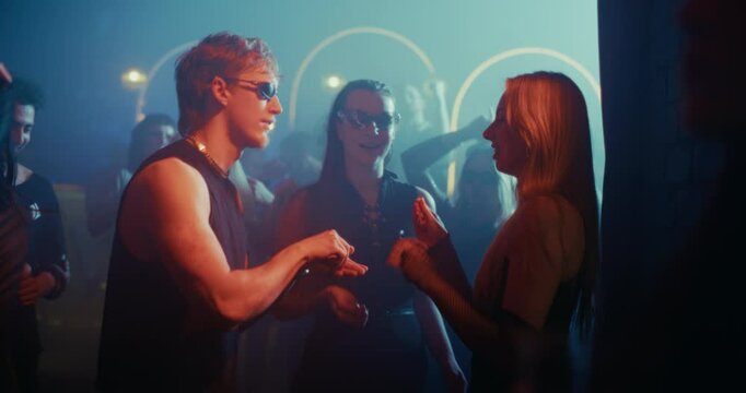 Man in Sunglasses Hands Party Drugs to Two Young Women in a Nightclub as Music Pulses and Lights Flash. Joyful Friends Laugh and Dance with Heightened Energy and Intensity