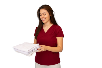 Young smiling masseuse holding a stack of clean white towels, showcasing professionalism and warmth against a transparent background