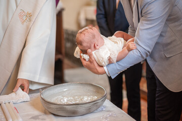 Un tout jeune bébé entrain de faire baptiser dans une église