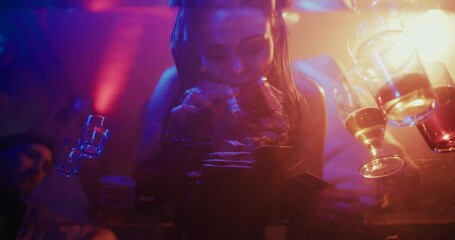 Cinematic Depiction of a Young Male and Female Taking Powder Drugs at a Party. Under-glass View of Two Party People During a Rowdy Night Out. Club Lights Flash Above as Energy Builds