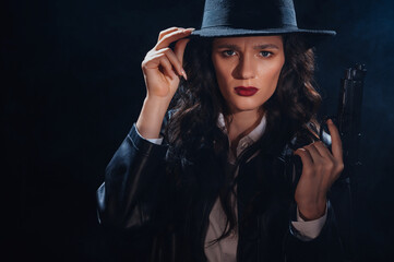 portrait of a female detective in a coat and hat with a gun in her hands. A book drama noir portrait in the style of detectives of the 1950s.