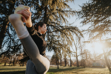 A young woman performs a stretching routine in a scenic park, embracing nature and fitness under...