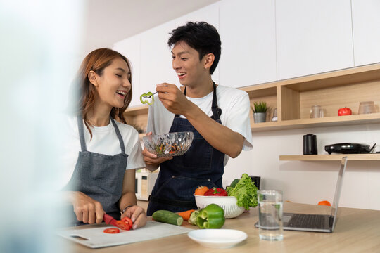 Couple Cooking Together. Joyful young couple preparing healthy meal in modern kitchen.