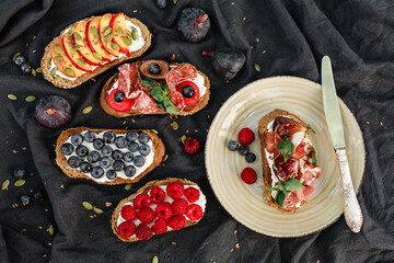 Bruschetta with labneh, prosciutto, salami, figs, peaches, cherry tomatoes, basil, and fresh berries. Rustic Italian-style appetizers with creative toppings