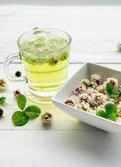 White clover Trifolium repens herbal tea in a clear glass. Steaming hot drink with glower blossoms...
