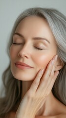 Beautiful woman with silver hair and closed eyes touching her face, conveying calmness and peace. Useful for advertising cosmetics and care treatments.