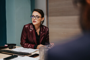 Focused professional woman wearing glasses and a stylish outfit engaged in a serious work...