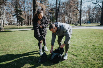 Obraz premium Two teenagers unpack their bags in a park surrounded by autumn trees under a clear sky, enjoying the outdoors and the fresh environment around them.