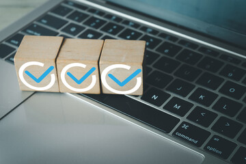 Wooden blocks with checkmark icon on a laptop keyboard.Concept for task completion,successful...