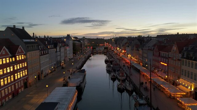 Aerial view of the historic Nyhavn waterfront, a 17th-century canal and entertainment district lined by brightly coloured townhouses, bars and restaurants, at dusk in Copenhagen, Denmark.	
