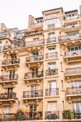 Detailed Facade of Parisian Apartment Building with Numerous Balconies and Plants