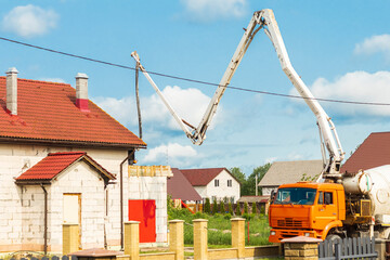 Concrete truck pours cement at residential construction site in rural area on a sunny day
