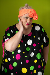 Plus size woman in vibrant polka dot outfit making a comic shrug gesture with outstretched hands and amusing expression.