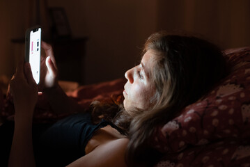 Depicts a common moment of sleeplessness due to smartphone overuse at night.