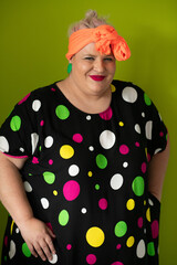 Plus size woman in vibrant polka dot outfit making a comic shrug gesture with outstretched hands and amusing expression.