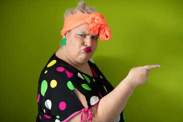 Plus size woman in vibrant polka dot outfit making a comic shrug gesture with outstretched hands and amusing expression.