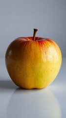 A Glossy Yellow Apple on a White Surface