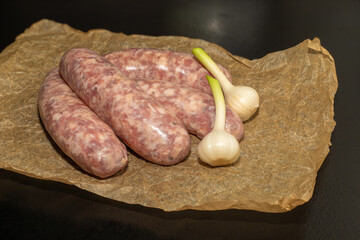 Meat sausages with garlic, prepared for grill, on parchment. Raw sausages for grill.