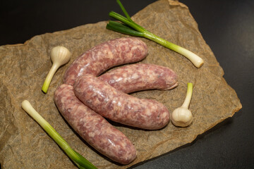 Meat sausages with garlic, prepared for grill, on parchment. Raw sausages for grill.
